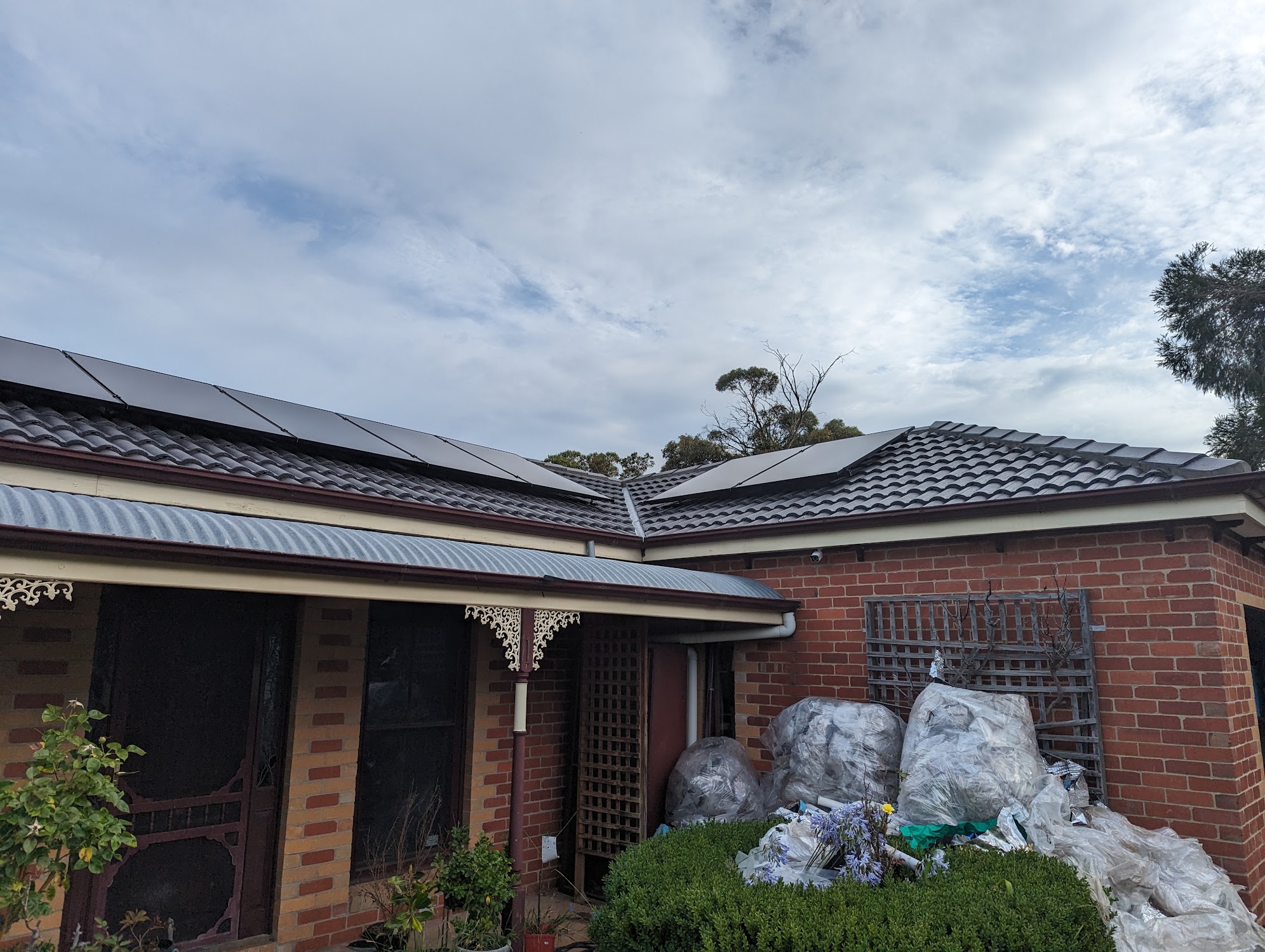 A brick home with a freshly laid dark tile roof and materials still in the yard