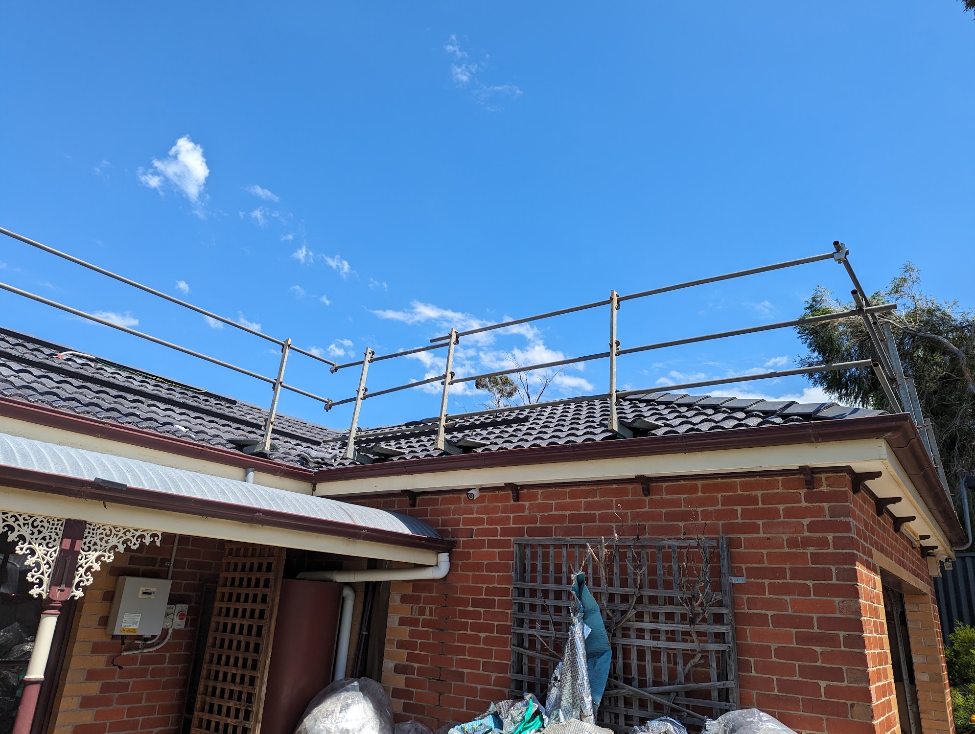 Safety rails along the edge of a re-roofed brick home under blue sky
