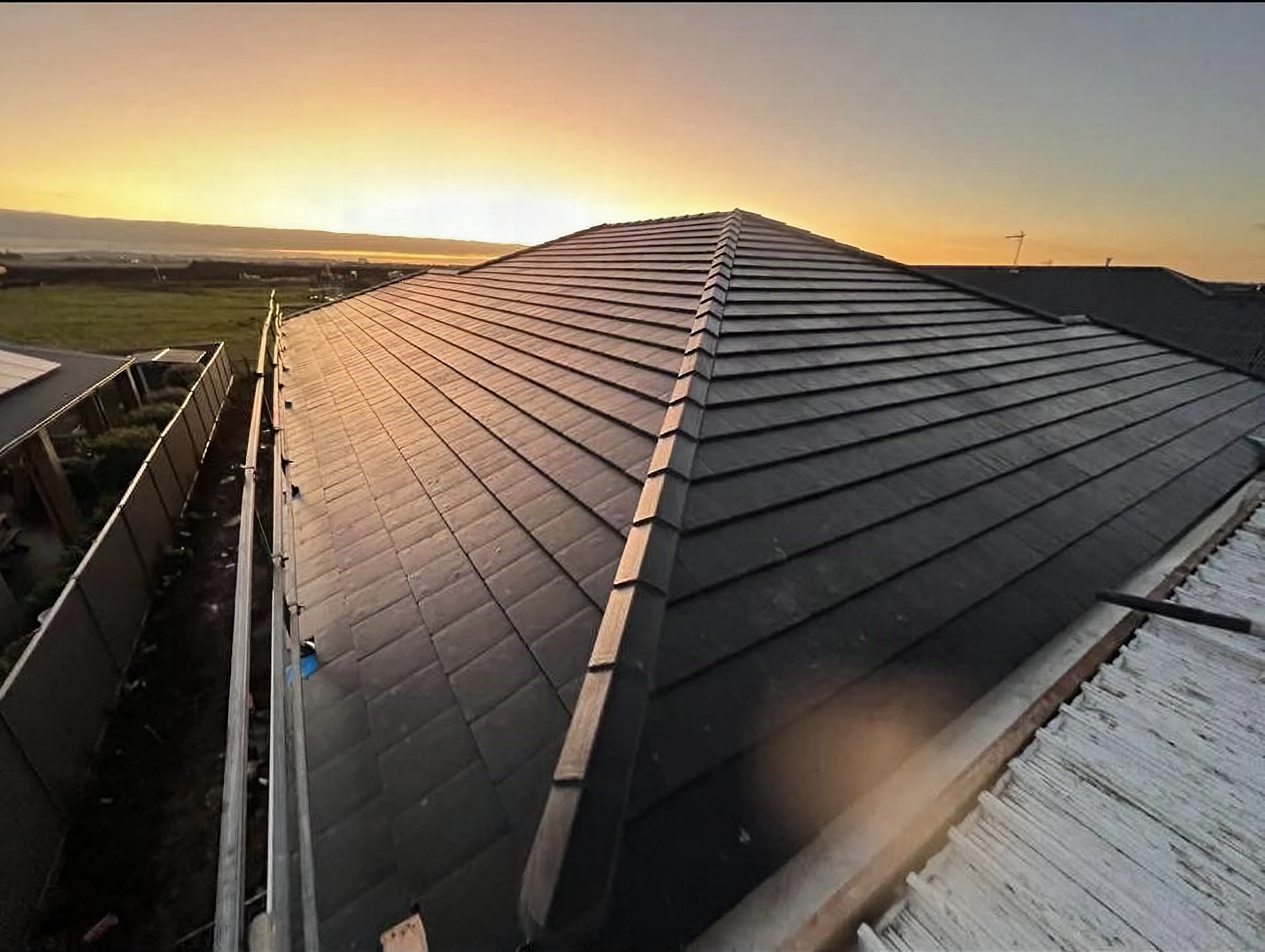 A newly tiled hip roof catching first light over open country outside Ballarat