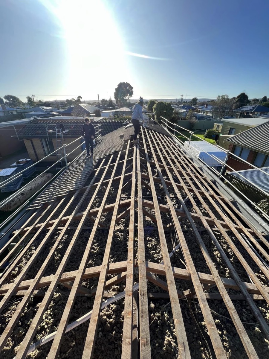 A roof stripped back to bare timber battens with the sun low behind it