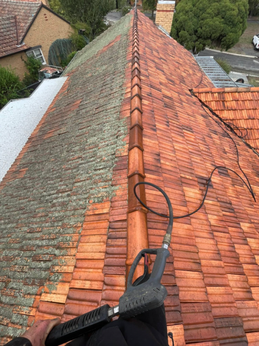 A terracotta tile roof being washed down along the ridge line