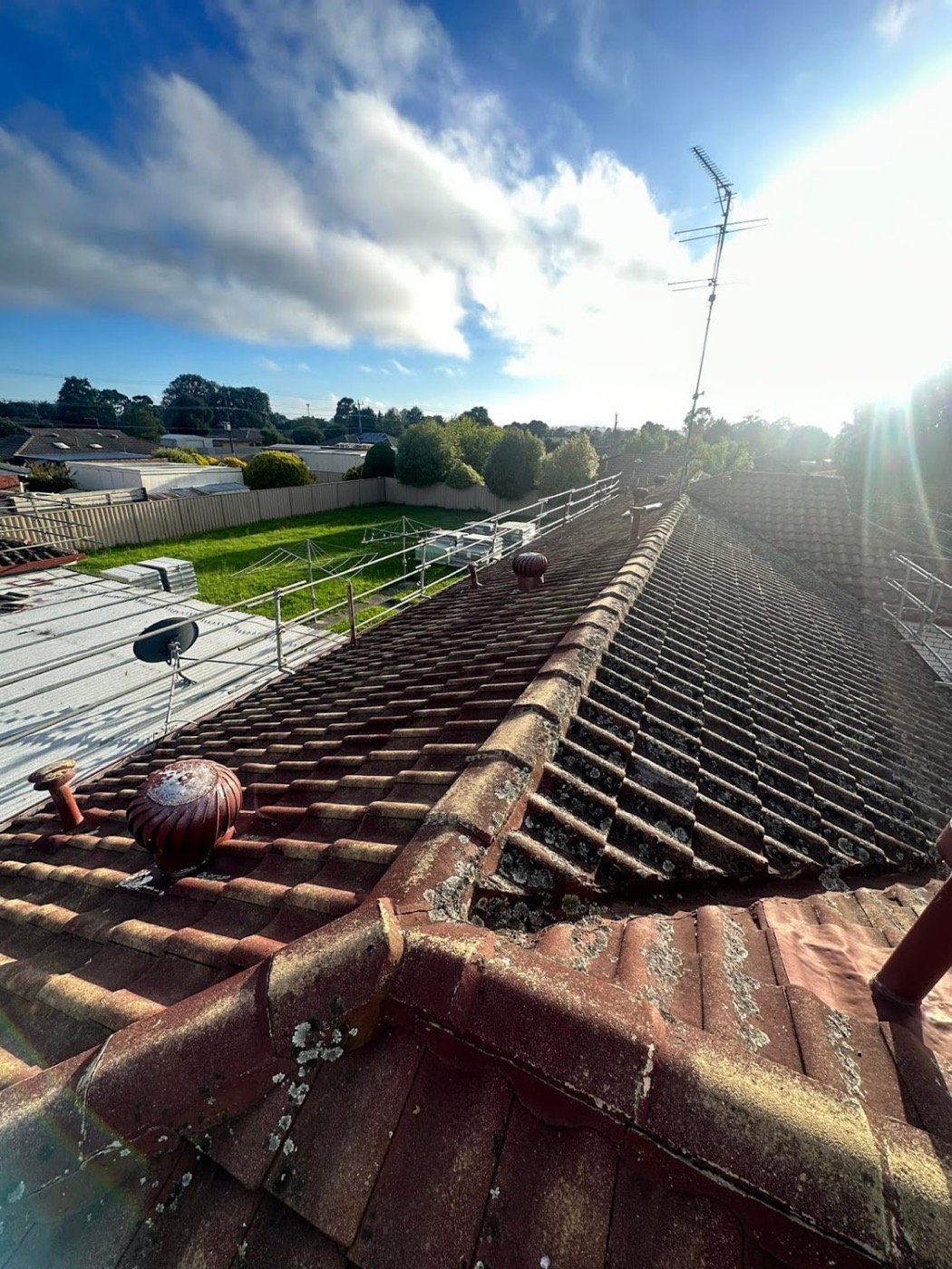 A terracotta tile roof ridge with the sun breaking over it