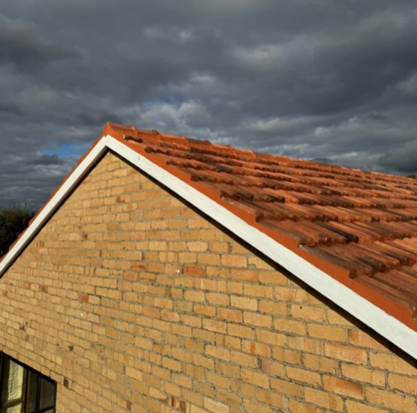 A cream brick home with a terracotta tile gable end