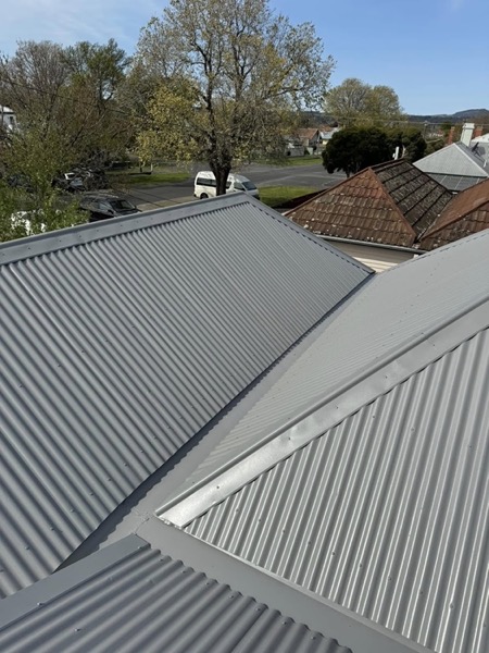 Two silver corrugated roof planes meeting at a hip