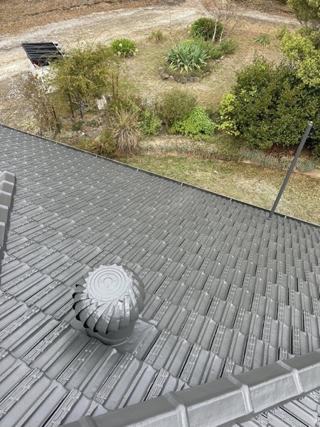 A grey tile roof with a whirlybird vent fitted near the ridge