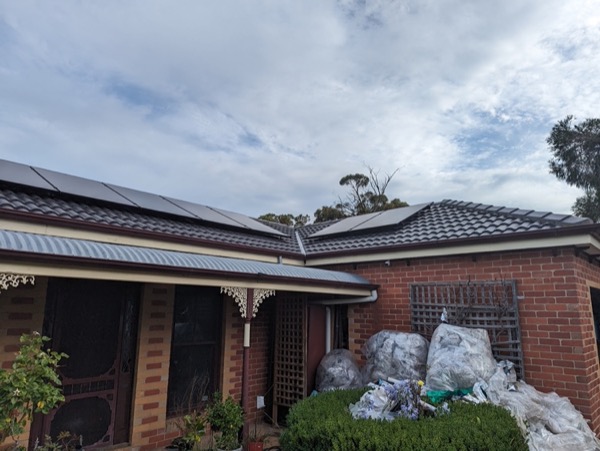 A brick home with a freshly laid dark tile roof and materials in the yard