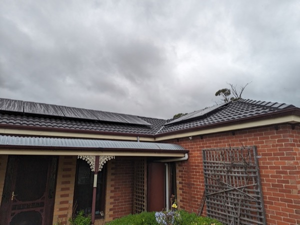 A brick verandah home with a new dark roof under heavy cloud