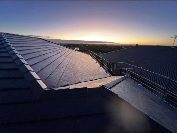 A new tile roof and box gutter under a violet dusk sky