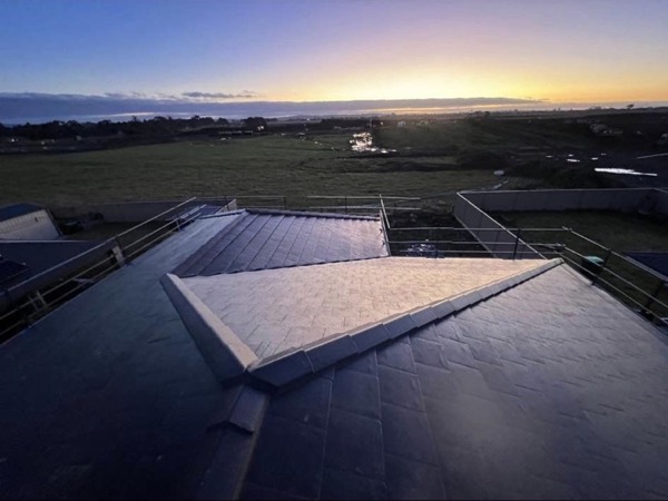 Dawn light over a low roof and the paddocks beyond it