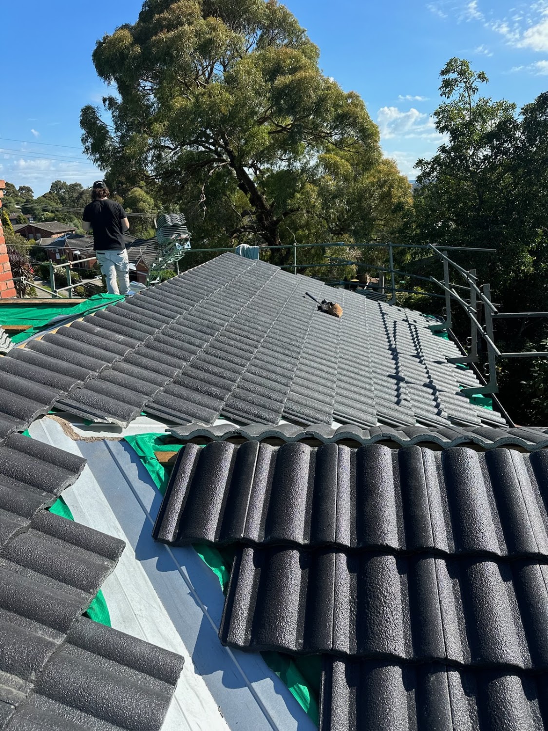 New charcoal tiles being laid over green sarking on a Ballarat home
